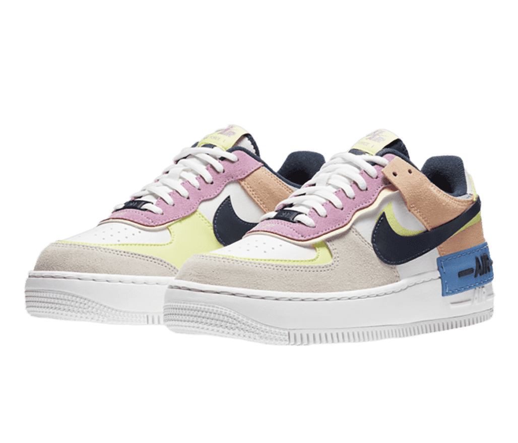 A pair of AF1 Low “Photon Dust” sneakers in light beige, tan, pink, and lime suede, a black leather Nike Swoosh, and a blue rubber logo overlay on the heel.