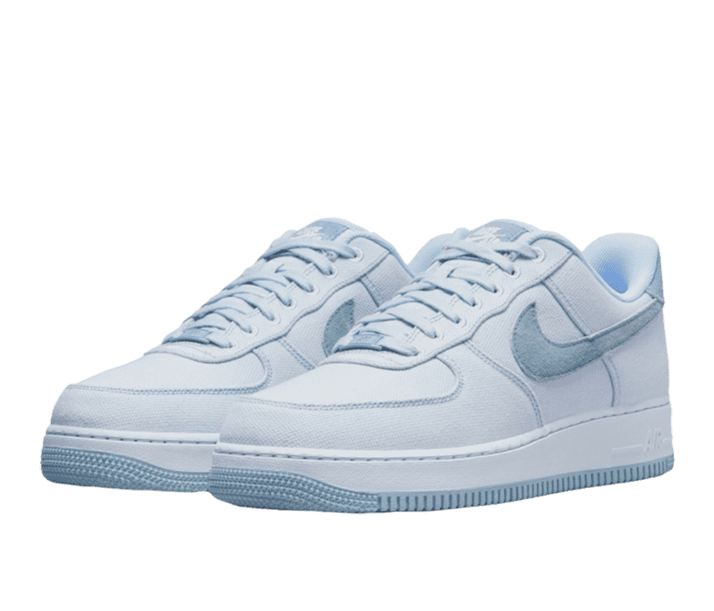 A pair of Nike Air Force 1s made of light blue canvas. The sole is blue to match the upper, and the Nike swoosh is in a darker blue suede.
