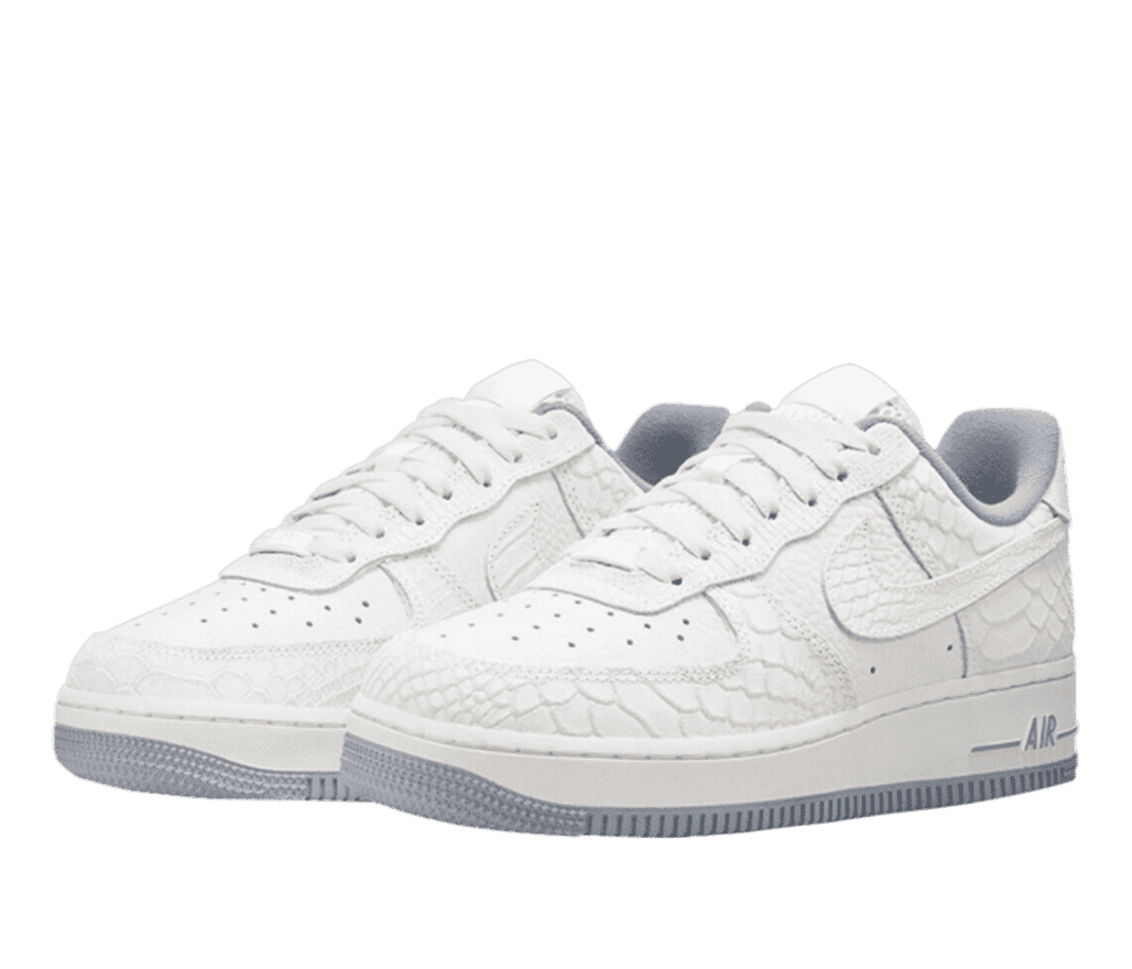 A pair of white and grey leather Nike Air Force 1s. The shoe is primarily white with gray accents on the bottom of the sole. The AIR logotype on the sole and the shoe interior are also a matching gray. The leather of the toe and heel sport a snakeskin-like pattern.