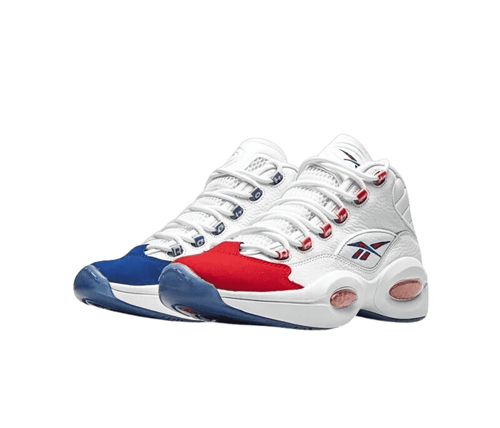 A white pair of Reebok Question Mid sneakers with a red Reebok logo—outlined in blue—on the sides, blue toe guards, and red and blue toeboxes on the left and right shoe.
