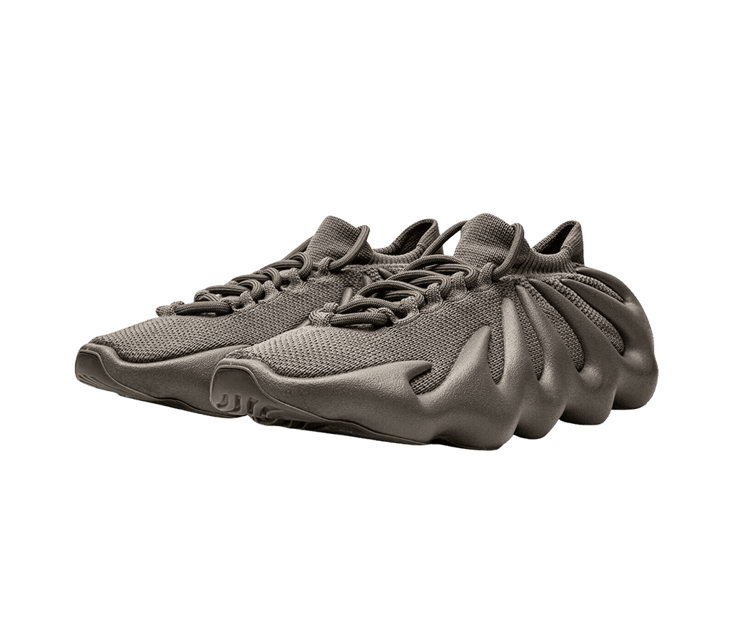 A pair of Adidas Yeezy 450 “Cinder” sneakers in a dark monochromatic tan colorway with a cuffed collar and rubber soles with a wavy design reaching to the top of the shoe.