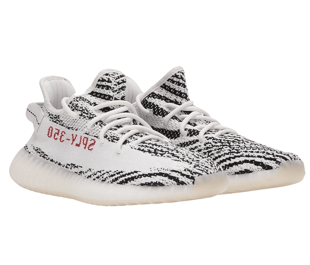 A white pair of Adidas Yeezy sneakers covered in black pixelated spiral patterns. The soles are semi-translucent with a yellow tint and “SPLY-350” is written backwards in red, on the lateral sides.